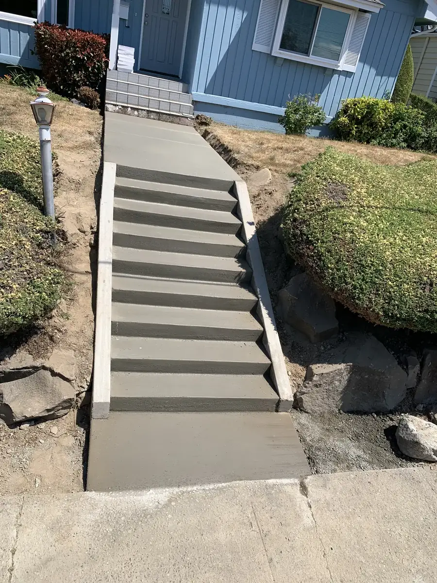Long run of new concrete front-yard stairs leading to a house in Olympia, WA
