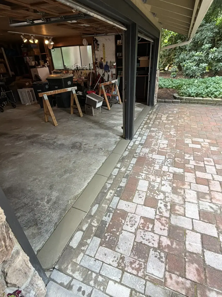 New garage floor concrete slab poured next to an existing brick paver patio in Olympia, WA